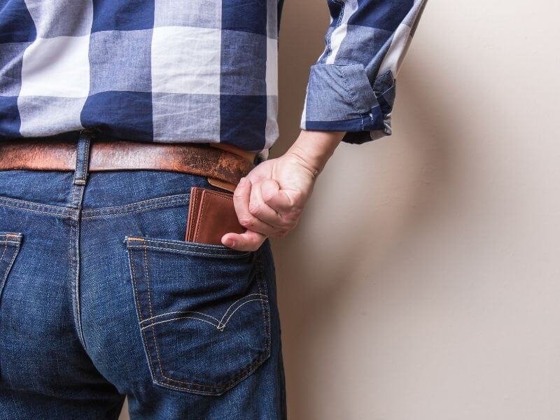 Joven sacando la billetera del bolsillo, simbolizando el ahorro en consultas médicas sin costo de honorarios.