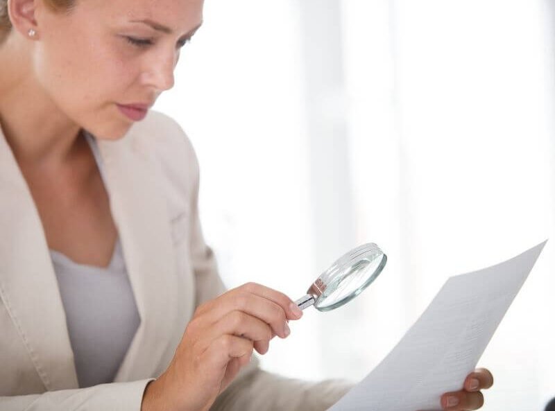 Mujer revisando un documento con lupa antes de contratar un seguro Metalife Mujer de MetLife