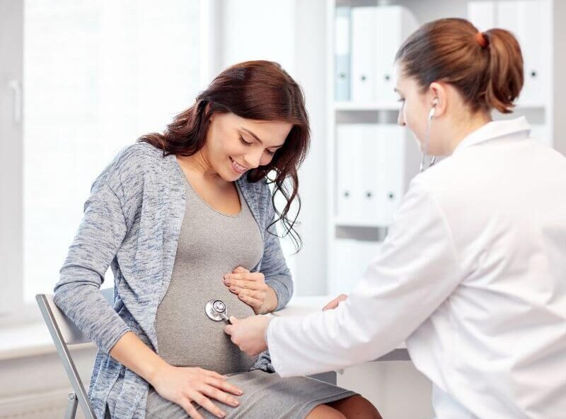 Mujer embarazada hablando con un médico sobre seguro para embarazadas y maternidad en un hospital privado